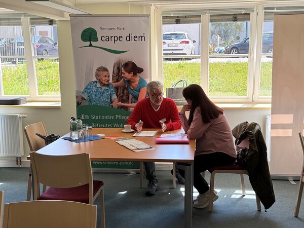 Tisch mit zwei sitzenden Personen, die sich unterhalten.