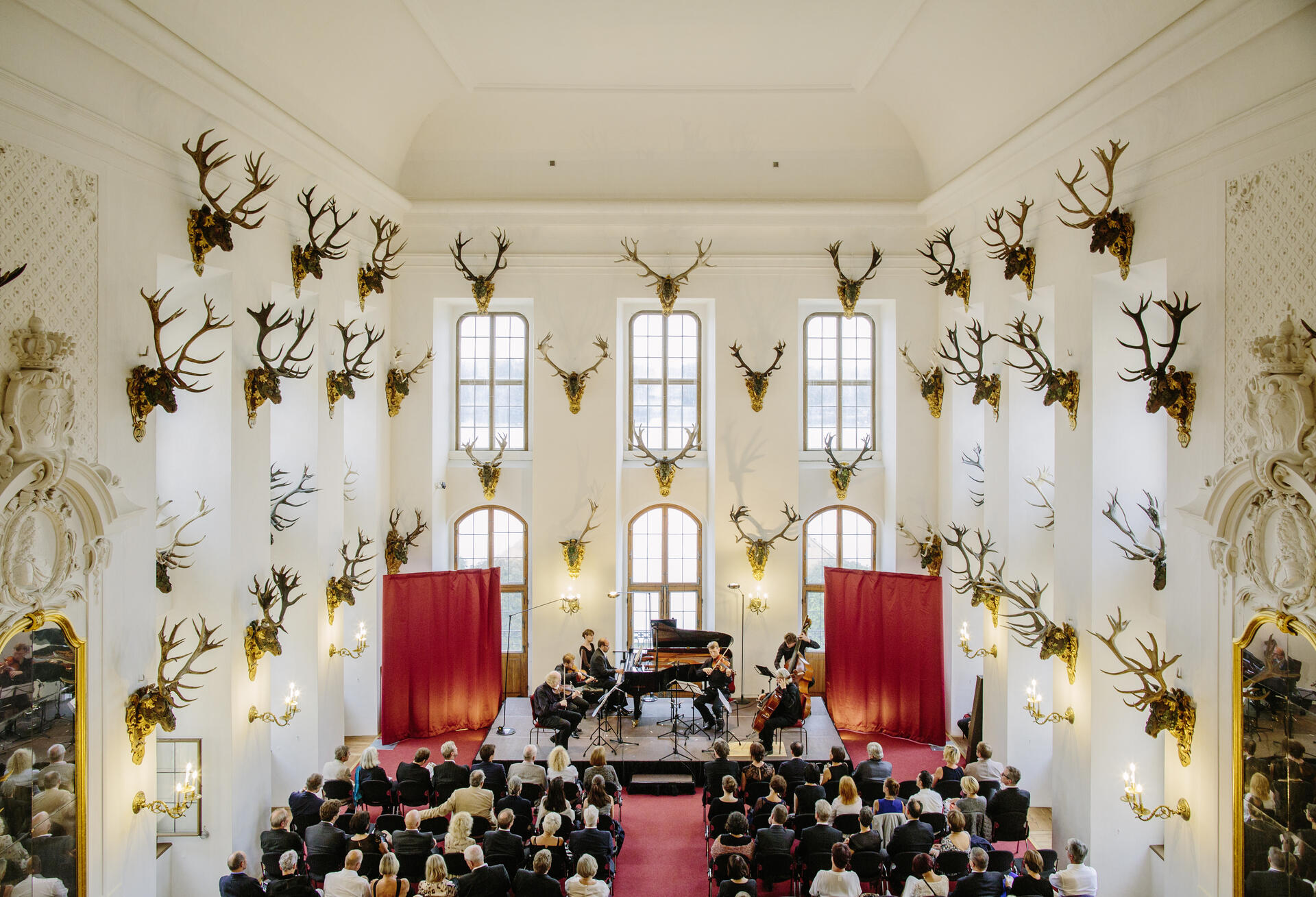 Bild vergrößern: Ein Ensemble in einem großen Raum des Schlosses Moritzburg mit Zuhörern.