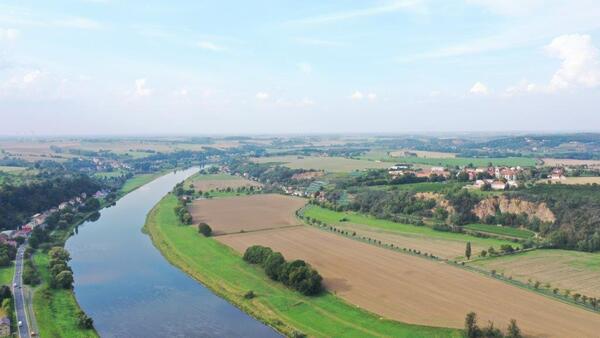 Bild vergr&ouml;&szlig;ern: Blick auf die Elbe und Felder mit einer Ortschaft in der Gemeinde Diera-Zehren.