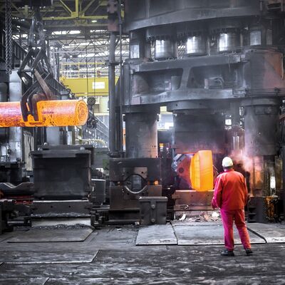 Bild vergrößern: Arbeiter im Schmiedewerk mit glühendem Metall.
